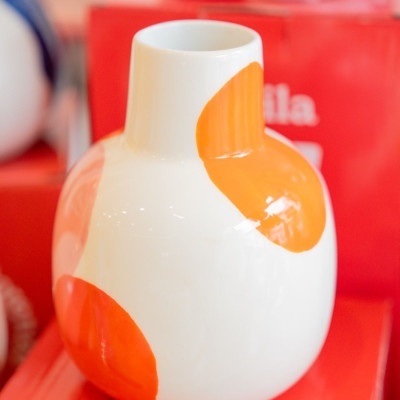 Vaso branco com manchas laranja brilhantes sobre superfície vermelha