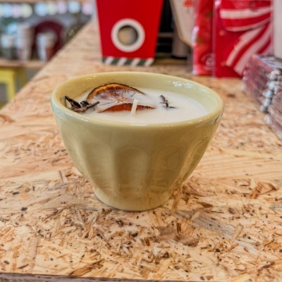 Vela branca em tigela de cerâmica creme com decoração seca na madeira.