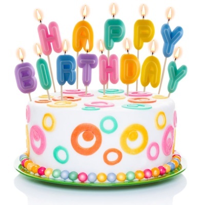 Bolo branco decorado com círculos coloridos e velas coloridas acesas com a frase HAPPY BIRTHDAY