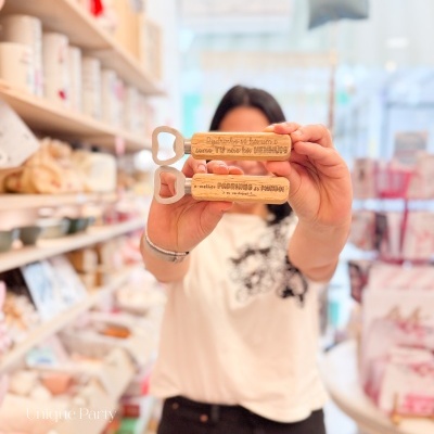 Dois abridores de garrafas com cabo em madeira e texto gravado a ser exibidos por uma pessoa numa loja