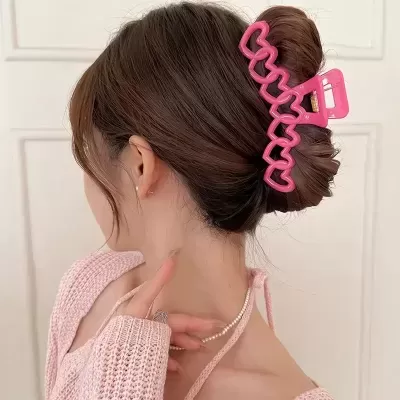 Mulher com grampo de cabelo rosa e suéter rosa claro