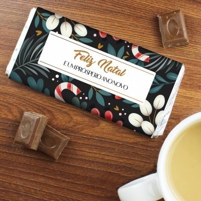 Barra de chocolate natalícia com embalagem preta decorada e chávena de chá ao lado