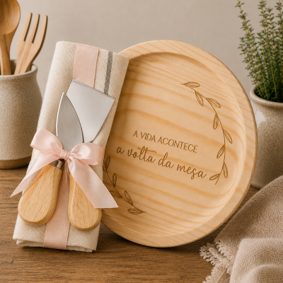 Tábua redonda de madeira com gravação e utensílios de queijo com guardanapo em mesa de madeira.