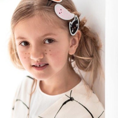 Menina com presilhas de cabelo de Halloween e blusa branca com padrão preto