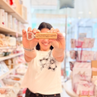 Pessoa segurando abridor de garrafas de madeira com texto gravado em loja