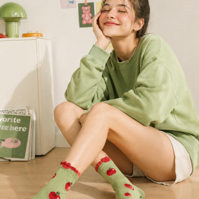 Meias verdes com maçãs vermelhas e sweat verde claro com calções brancos