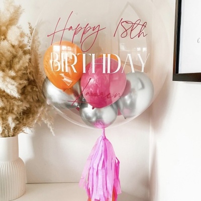 Balão transparente com pequenos balões coloridos e texto de aniversário decorativo