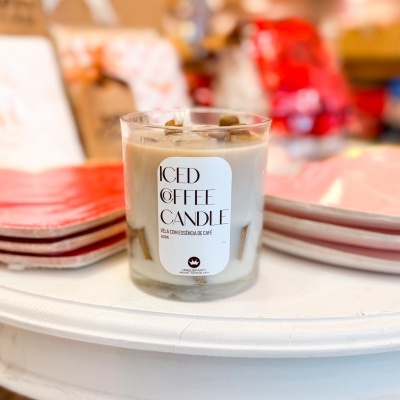 Vela de café gelado em vidro sobre mesa branca com pratos ao fundo