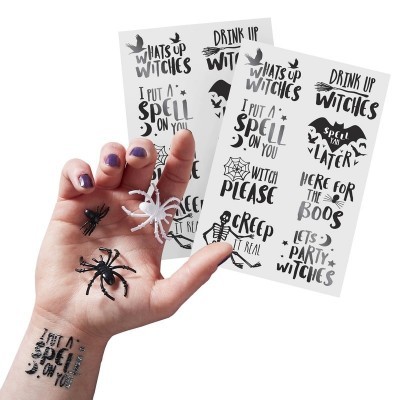 Mão com aranhas plásticas e folhas com frases de bruxas em inglês.