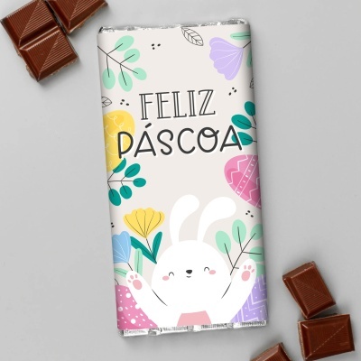 Barra de chocolate com embalagem decorada e pedaços de chocolate ao redor