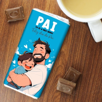 Barra de chocolate com embalagem azul e desenho de pai e filho abraçados, texto sobre mesa de madeira com pedaços de chocolate e chá