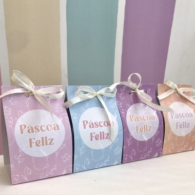 Quatro caixas pequenas coloridas com etiquetas 'Páscoa Feliz' e laços