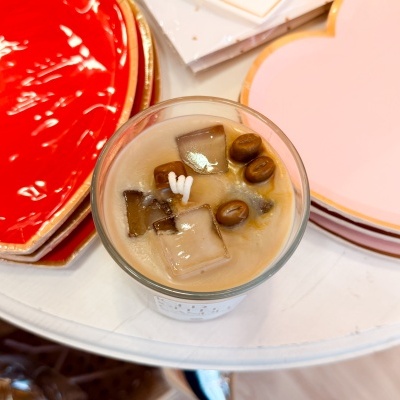 Bebida com gelo e café em copo transparente ao lado de pratos em forma de coração coloridos.