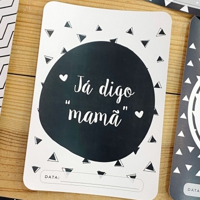 Cartões em papel preto e branco com frases e espaço para datas sobre mesa de madeira