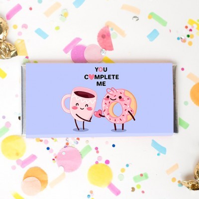 Embalagem lilás com chávena de café e rosquinha ilustradas e texto YOU COMPLETE ME