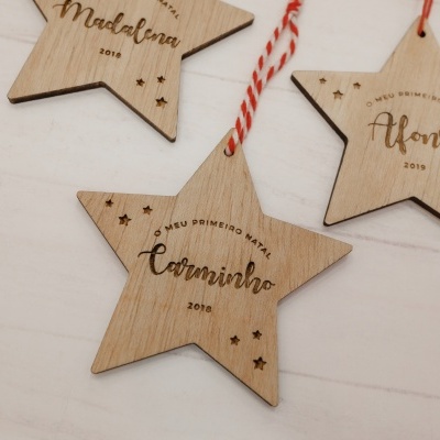 Ornamentos de estrela em madeira clara com gravações a laser e cordão vermelho e branco