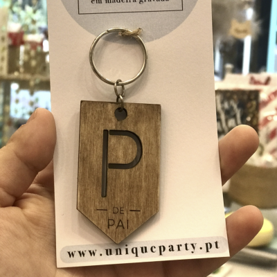 Porta-chaves em madeira gravada com letra P e texto DE PAI num cartão branco