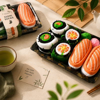Conjunto de meias que parecem sushi, com embalagem e acessórios de chá num ambiente minimalista.