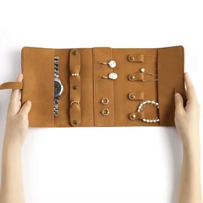 Estojo de couro castanho aberto com bijutaria e relógio