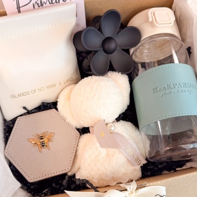 Conjunto de presente com itens complementares como bolsa, estojo, chaveiro e garrafa dentro de caixa de presente.