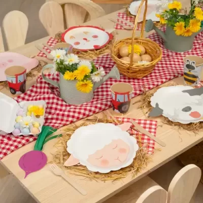 Mesa decorada para festa infantil com pratos temáticos de animais e decoração de mesa rústica com flores e ovos.