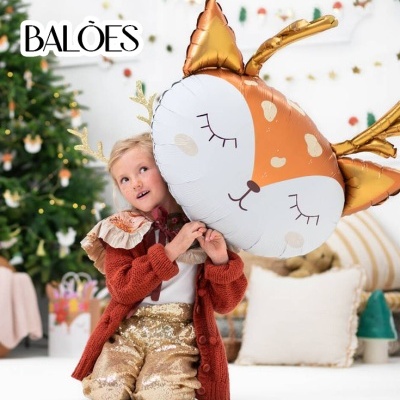 Criança sentada segurando balão em forma de veado em ambiente natalício