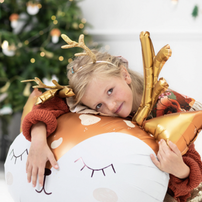 Criança abraça almofada balão forma rena castanha branca e dourada com chifres dourados