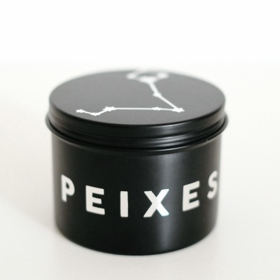 Frasco preto com escrita branca 'PEIXES' e desenho de constelação na tampa