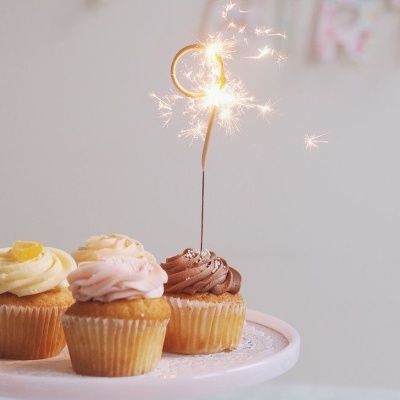 Três cupcakes coloridos com vela de faísca nº 9 acesa