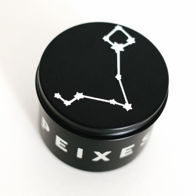 Frasco preto com tampa com desenho branco de constelação e texto PEIXES