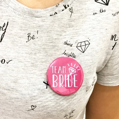 Botão rosa TEAM BRIDE em t-shirt cinza com estampas pretas