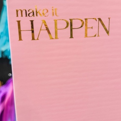 Cartão rosa com texto dourado 'make it HAPPEN'