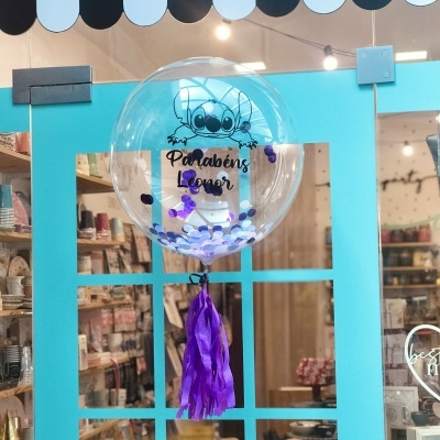 Balão transparente com texto de parabéns suspenso numa porta azul