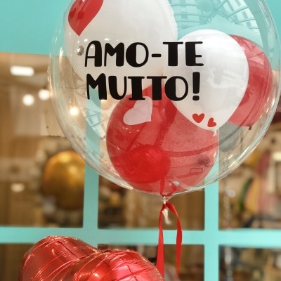 Balão transparente com balões interiores brancos e vermelhos com texto 'AMO-TE MUITO!'
