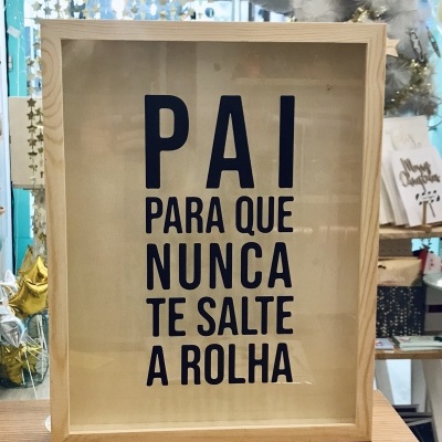 Quadro de madeira com texto em preto sobre fundo claro, em ambiente com decoração de Natal.