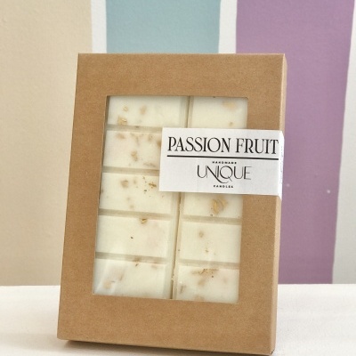 Caixa de vela artesanal Passion Fruit com pedaços visíveis, em caixa de cartão castanho com janela transparente