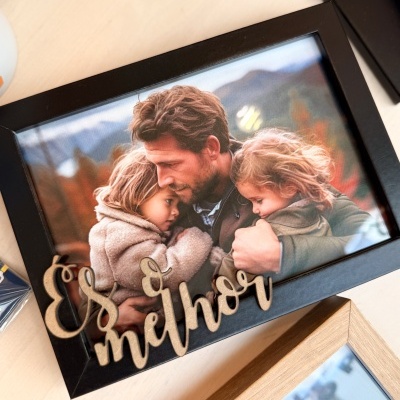 Moldura preta com fotografia de um homem a abraçar duas crianças pequenas com decoração em madeira 'És melhor'