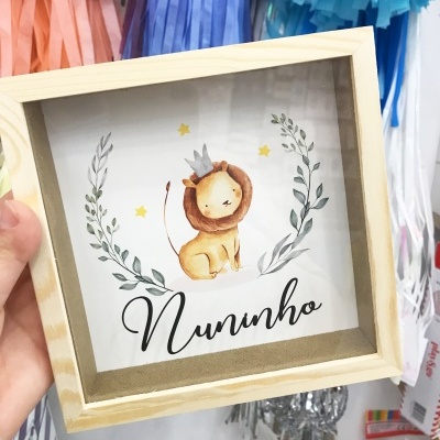 Quadro decorativo com ilustração de leão e texto Nuninho numa moldura de madeira clara