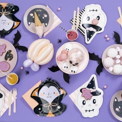 Conjunto de festa de Halloween com pratos decorados, copos com bebidas, talheres de madeira e doces sobre toalha roxa