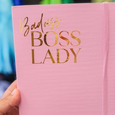 Caderno rosa com texto dourado 'Badass BOSS LADY' e elástico lateral