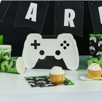 Prato em formato de comando, copos e guardanapos verdes com desenhos de videojogo, cupcake, faixa preta com letras brancas