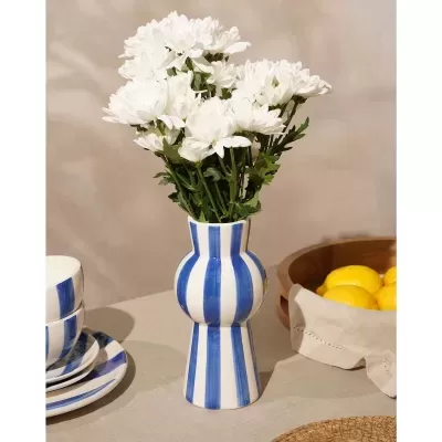 Vaso cerâmico azul e branco com flores brancas e limões ao lado