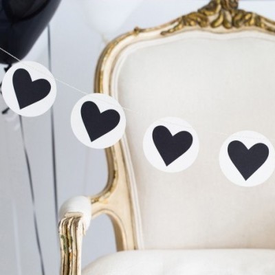 Guirlanda com corações pretos pendurada numa cadeira branca com detalhes dourados