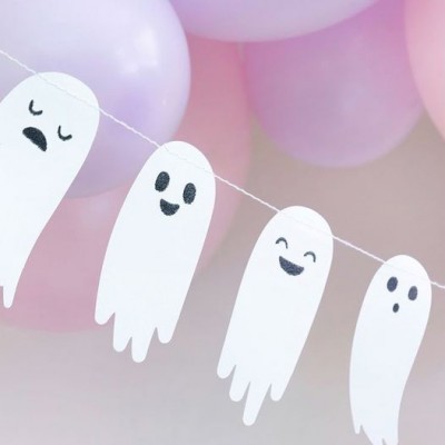Guirlanda de fantasmas de papel brancos com expressões faciais pendurada em fio com balões cor de rosa e lilás ao fundo