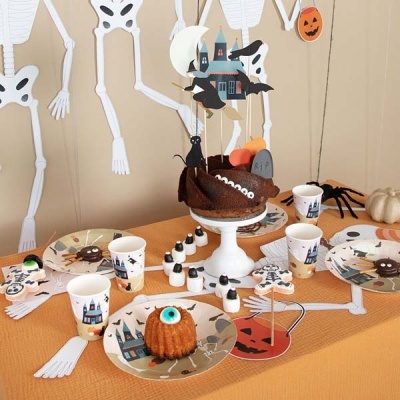 Mesa de festa com decoração e comida temática de Halloween com esqueletos na parede