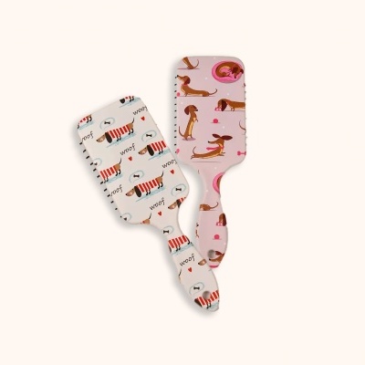 Duas escovas de cabelo com padrão de cães em fundo branco e rosa