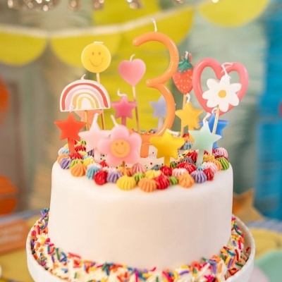 Bolo branco decorado com velas coloridas e confetes.