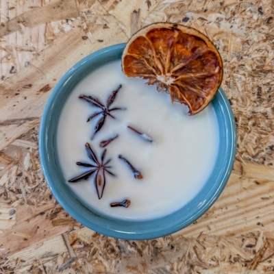 Vela branca em tigela azul com especiarias e fatia seca de laranja em madeira