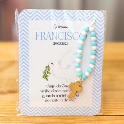 Pulseira colorida com crucifixo em cartão de batizado com texto em português.