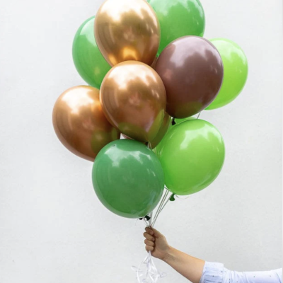 Mãos segurando balões dourados e verdes contra fundo branco